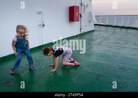 Zwei Mädchen spielen an Deck im Wind auf einem Kreuzfahrtschiff, das auf einer Ostseekreuzfahrt zwischen Helsinki in Finnland, Åland und Stockholm in Schweden unterwegs ist Stockfoto