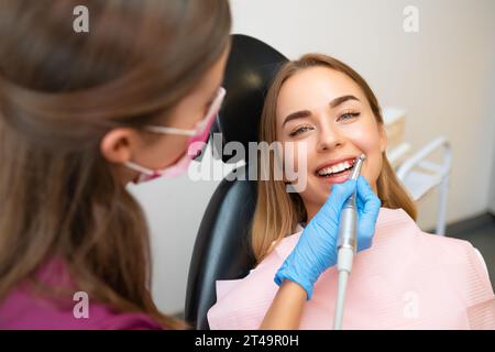 Eine attraktive junge Frau lässt ihre Zähne in einer Stomatologie-Klinik professionell reinigen und pflegen. Stockfoto