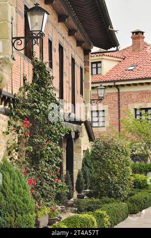 Ein altes Haus aus Backstein und Holzbalken, das mit üppigen Kletterpflanzen in Santillana del Mar geschmückt ist Stockfoto