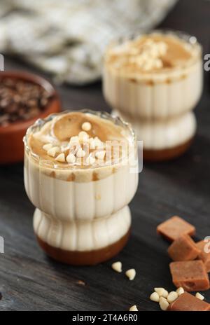 Zwei Gläser Caramel Dalgona Kaffee mit weißer Schokoladenplatte Stockfoto