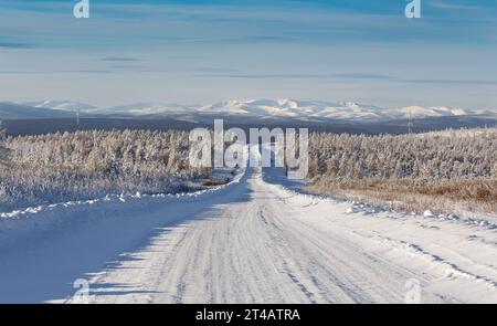Winterstraße am Hang des Hügels vor dem Hintergrund des Zverev-Kammes in Süd-Yakutia, Russland Stockfoto