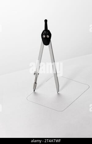 Mit einem Kompass wird ein Quadrat auf Papier gezeichnet. Unmögliches Konzept. Stockfoto