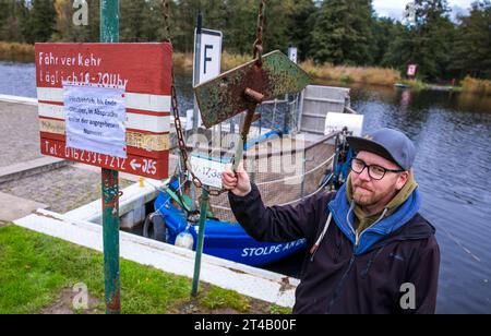 Stolpe, Deutschland. Oktober 2023. Der Fährmann Ulf Radicke steht am Pier der kleinen Passagierfähre über die Peene und wartet auf Passagiere. Von März bis Oktober können Wanderer oder Radfahrer die fast 100 Meter über den Fluss überqueren. Die nun zu Ende gehende Saison könnte jedoch ihre letzte sein – die einzige Fußgängerfähre zwischen Anklam und Jarmen ist wegen fehlender finanzieller Unterstützung durch den Bezirk von der Schließung bedroht. Die Gemeinde hat daher eine Kampagne zur Rettung der Fähre gestartet. Jetzt werden 2.000 Unterschriften gesammelt, bis der Bezirk Credit: dpa/Alamy Live News Stockfoto