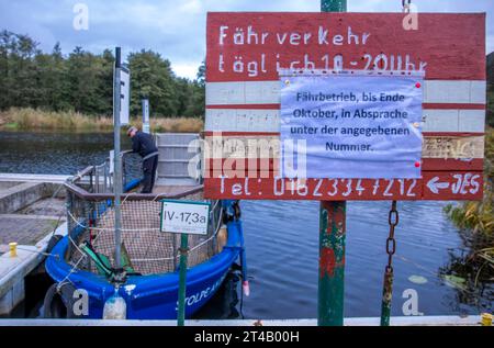 Stolpe, Deutschland. Oktober 2023. Ein Schild hängt am Pier der kleinen Passagierfähre über die Peene und informiert über die Reisezeiten und die Erreichbarkeit des Fährmannes. Von März bis Oktober können Wanderer oder Radfahrer die fast 100 Meter über den Fluss überqueren. Die nun zu Ende gehende Saison könnte jedoch ihre letzte sein – die einzige Fußgängerfähre zwischen Anklam und Jarmen ist wegen fehlender finanzieller Unterstützung durch den Bezirk von der Schließung bedroht. Die Gemeinde hat daher eine Kampagne zur Rettung der Fähre gestartet. Jetzt werden 2.000 Unterschriften Col Credit: dpa/Alamy Live News sein Stockfoto