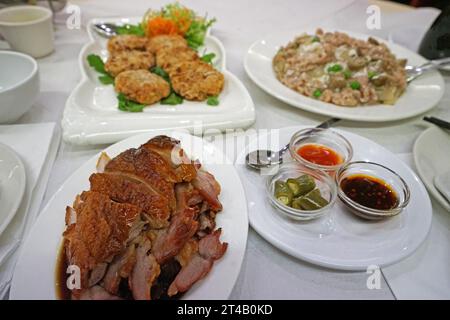 Verschiedene chinesische Gerichte - Schweinenudel mit schwarzer Sojasauce, serviert mit frittiertem Fischkuchen und gebratener Honigente Stockfoto