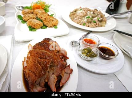 Verschiedene chinesische Gerichte - Schweinenudel mit schwarzer Sojasauce, serviert mit frittiertem Fischkuchen und gebratener Honigente Stockfoto