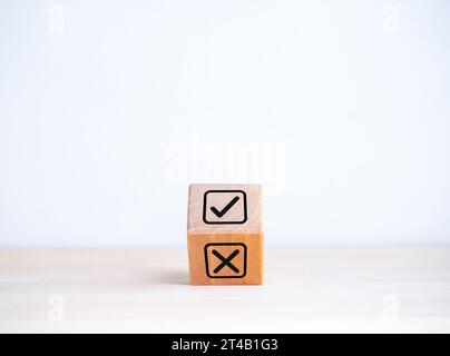 Entscheidung, richtig oder falsch wählen, positiv oder negativ, ja oder nein Konzepte. Häkchen Sie das Symbol X und kreuzen Sie es im Kontrollkästchen auf dem umkehrenden Holzwürfel bl Stockfoto