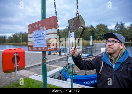 Stolpe, Deutschland. Oktober 2023. Ein Mann schlägt am Anleger der kleinen Passagierfähre über die Peene auf ein Eisen und informiert den Fährmann über das Signal. Von März bis Oktober können Wanderer oder Radfahrer die fast 100 Meter über den Fluss überqueren. Die nun zu Ende gehende Saison könnte jedoch ihre letzte sein – die einzige Fußgängerfähre zwischen Anklam und Jarmen ist wegen fehlender finanzieller Unterstützung durch den Bezirk von der Schließung bedroht. Die Gemeinde hat daher eine Kampagne zur Rettung der Fähre gestartet. Jetzt werden 2.000 Unterschriften gesammelt, bis Credit: dpa/Alamy Live News Stockfoto