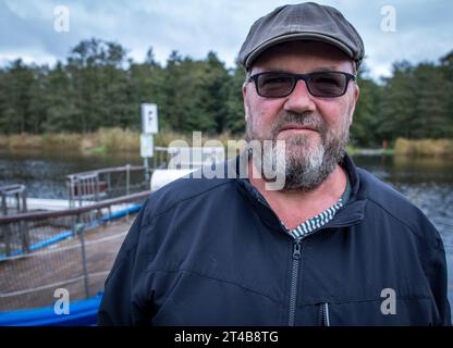 Stolpe, Deutschland. Oktober 2023. Der Fährmann Ulf Radicke steht am Pier der kleinen Passagierfähre über die Peene und wartet auf Passagiere. Von März bis Oktober können Wanderer oder Radfahrer die fast 100 Meter über den Fluss überqueren. Die nun zu Ende gehende Saison könnte jedoch ihre letzte sein – die einzige Fußgängerfähre zwischen Anklam und Jarmen ist wegen fehlender finanzieller Unterstützung durch den Bezirk von der Schließung bedroht. Die Gemeinde hat daher eine Kampagne zur Rettung der Fähre gestartet. Jetzt werden 2.000 Unterschriften gesammelt, bis der Bezirk Credit: dpa/Alamy Live News Stockfoto