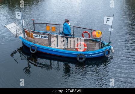 Stolpe, Deutschland. Oktober 2023. Der Fährmann Ulf Radicke fährt mit einem Passagier auf der kleinen Passagierfähre über die Peene (Luftaufnahme mit einer Drohne). Von März bis Oktober können Wanderer oder Radfahrer die fast 100 Meter über den Fluss überqueren. Die nun zu Ende gehende Saison könnte jedoch ihre letzte sein – die einzige Fußgängerfähre zwischen Anklam und Jarmen ist wegen fehlender finanzieller Unterstützung durch den Bezirk von der Schließung bedroht. Die Gemeinde hat daher eine Kampagne zur Rettung der Fähre gestartet. Jetzt werden 2.000 Unterschriften gesammelt, und zwar unter Angabe von dpa/Alamy Live News Stockfoto