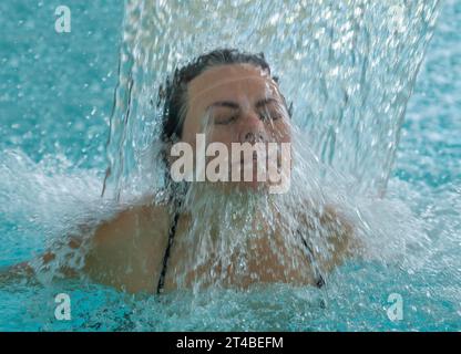 Frau Gesicht mit geschlossenen Augen genießt in einem Wasserfall in einem SPA Pool in der Schweiz Stockfoto