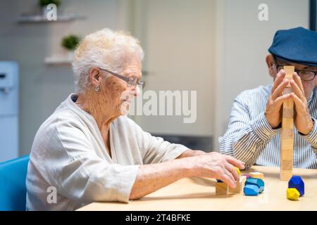 Alte Frau und Mann in einem Pflegeheim, die Geschicklichkeitsspiele spielen Stockfoto