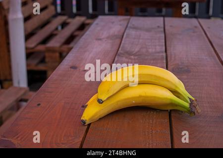 Bananen auf Holztisch auf der Veranda draußen Stockfoto