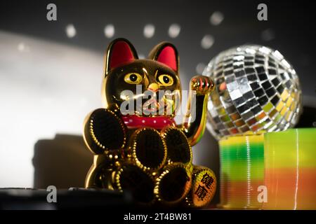 Chinesische Katze Bringt Glück. Artikel im Regal. Blendung von Licht auf Objekten. Goldfarbenes Spielzeug. Stockfoto