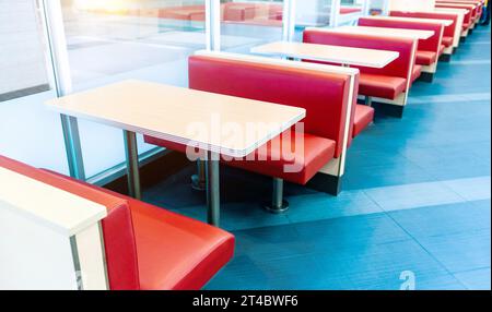 Leeres Fastfood-Restaurant mit roten Stühlen und Tisch in einer Reihe Stockfoto