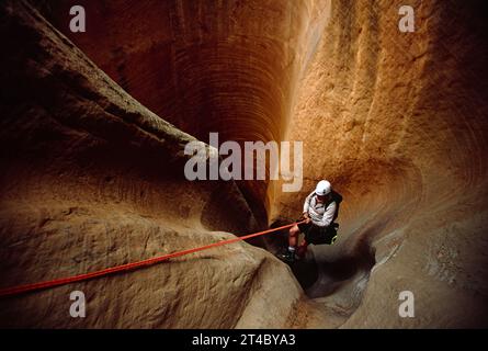 Ein Mann, der sich in einen Wüstenschlucht abseilt. Stockfoto