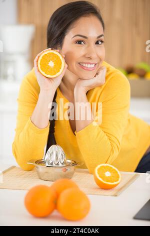 Schöne Frau, die Orangen drückt und Orangenhälfte zeigt Stockfoto