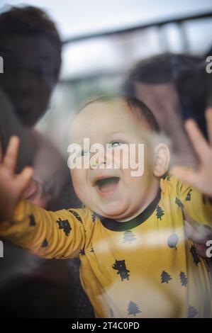 Porträt eines süßen lächelnden Jungen, der durch das Fenster schaut. Freude und Glück Konzept. Liebe und familiäre Emotionen Stockfoto