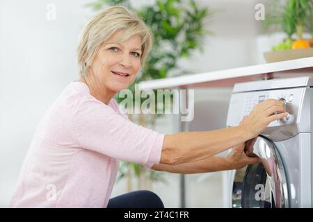 Ältere Frau laden Waschmaschine zu Hause Stockfoto