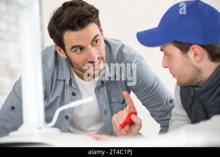 Ingenieur hilft männlichen Auszubildenden im Werk bei der Messung von Bauteilen Stockfoto