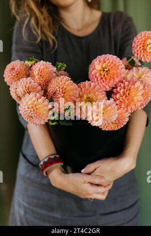 Frau, die Eimer der Dahlien hält Stockfoto