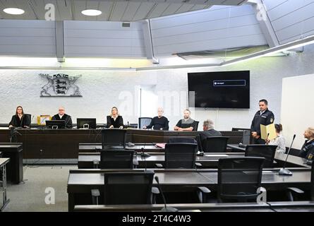 Stuttgart, Deutschland. 30. Oktober 2023. Die Angeklagte im Totschlag hält vor ihrem Gesicht eine Aktenhülle als Bildschirm, bevor der Prozess beginnt. 2. Von links, Vorsitzender Richter Norbert Winkelmann. Der Angeklagten wird vorgeworfen, im Mai 2023 in Reichenbach an der Fils ihren ehemaligen Partner mit ihrem Auto getroffen zu haben, die Reise mit dem ehemaligen Partner mehrere Kilometer am Fahrzeug festgeklammert und schließlich überfahren zu haben. Der frühere Partner starb später im Krankenhaus. Quelle: Bernd Weißbrod/dpa/Alamy Live News Stockfoto