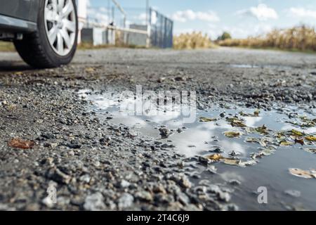 Pfützen mit Himmelsreflektion auf Schotterpiste Stockfoto