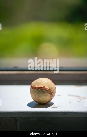 Der alte Baseballball sitzt auf der schmutzigen Fensterbank mit Kopierraum Stockfoto