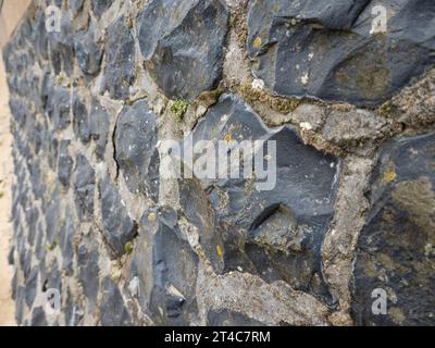 Schwarze Steinbrüche an der Wand befestigt mit Zement Stockfoto