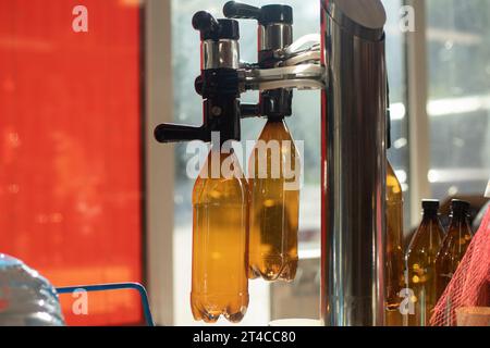 Getränke vom Fass. Alcol-Maschine zum Abfüllen von Kunststoffflaschen. Bier wird in die Flasche gegossen. Alkohol ist gesundheitsschädlich. Stockfoto