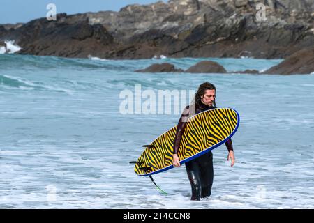 Ein Surfer mit seinem unverwechselbaren Surfbrett nach einer Surfsession in Fistral in Newquay in Cornwall in Großbritannien. Stockfoto