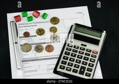 Dokument zur Grundsteuer mit Häusern, Kugelschreiber, Taschenrechner und Euro Stockfoto