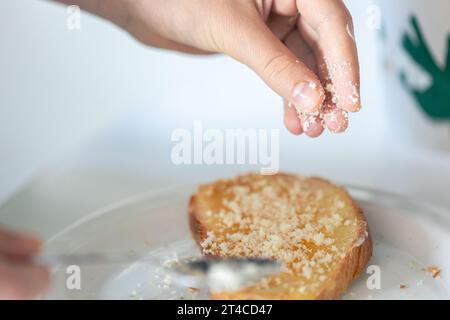 Eine Frau streut ein Stück Brot mit geriebenem Käse. Stockfoto