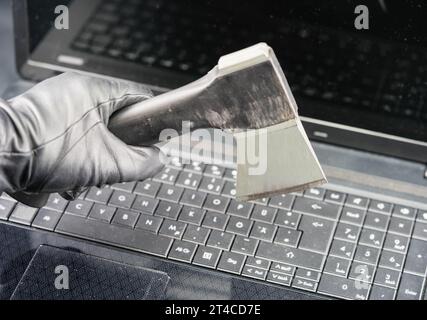Hand mit Handschuh, Axt über Tastatur mit Vorhängeschloss, Cyberangriff Stockfoto