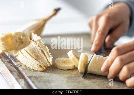 Eine Frau schneidet eine Banane auf einem Schneidebrett. Stockfoto