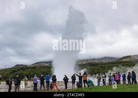 Umwerfende Touristen beobachten den ausbrechenden Geysir Strokkur, Island, Haukadalur Stockfoto