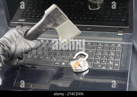 Hand mit Handschuh, Axt über Tastatur mit Vorhängeschloss, Cyberangriff Stockfoto