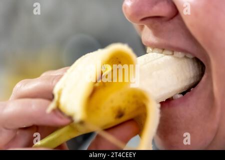 Eine Erwachsene Frau isst eine Banane, Nahaufnahme. Stockfoto