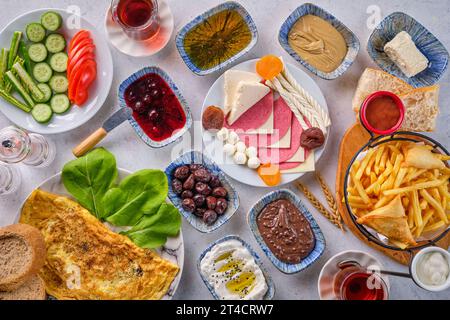 Eine Auswahl an Gerichten vom traditionellen türkischen Frühstück, einschließlich Oliven, Eier, Milch, Tee, Gemüse und Pommes frites Stockfoto