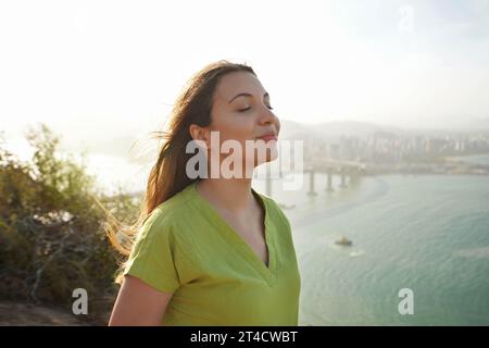 Schöne junge Frau mit geschlossenen Augen, die mit Wind auf ihrem Gesicht atmet und die Sonne bei Sonnenuntergang genießt. Schönheit Sonnenschein Mädchen Seitenprofil Porträt. Po Stockfoto