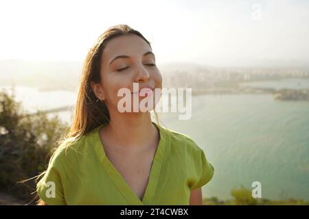Glückliche Reisende Frau genießt entspannten Wind auf Gesicht bei Sonnenuntergang in ihrem Urlaub in Brasilien. Mächtige und friedliche Frau, die sich ihres potenziellen Konzepts bewusst ist. Stockfoto