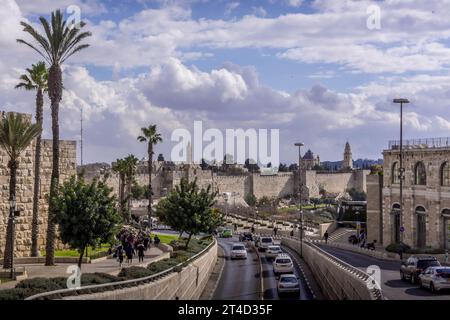 Der Straßenverkehr auf der Jerusalemer Autobahn entlang der Mauern der Altstadt mit den Palmen und dem bewölkten Himmel in Israel. Stockfoto