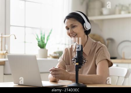 Frau spricht während eines Webinars oder Podcasts zu Hause ins Mikrofon Stockfoto