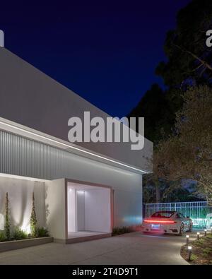 Außenansicht in der Abenddämmerung mit Porsche. Oceanus House, Los Angeles, Usa. Architekt: Pierre De Angelis, 2023. Stockfoto