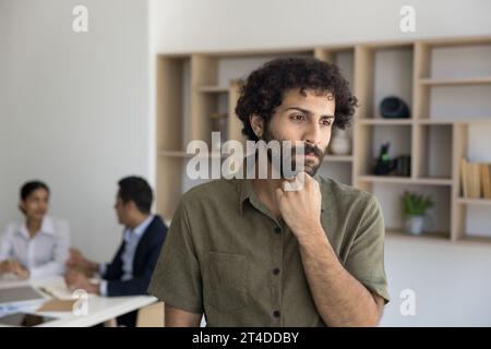 Ernsthafter junger arabischer Geschäftsmann, der im Besprechungsraum denkt Stockfoto