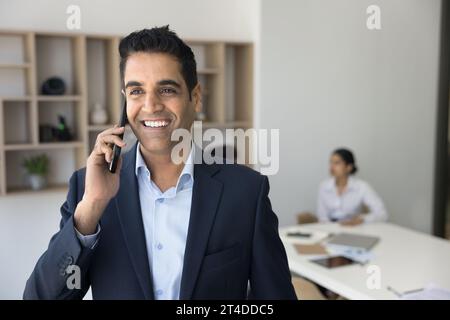 Fröhlicher, erfolgreicher, gutaussehender Geschäftsmann, der Mobiltelefonanrufe genießt Stockfoto