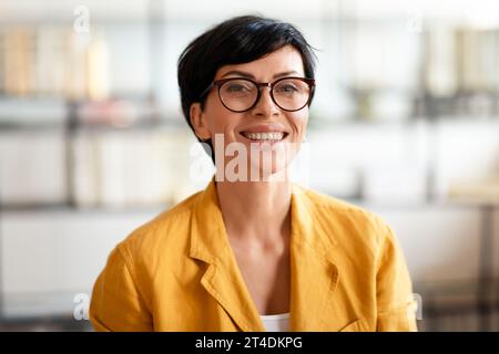 Eine europäische Geschäftsfrau mittleren Alters lächelte in die Kamera und trug eine Brille drinnen Stockfoto