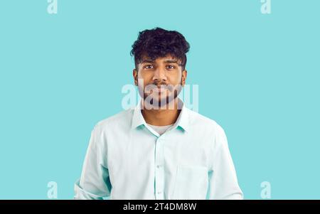Studio-Aufnahme eines jungen Indianers in einem weißen Hemd, der auf blauem Hintergrund steht Stockfoto