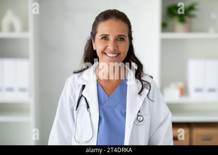 Porträt einer fröhlichen reiferen Ärztin, die in der Klinik posiert Stockfoto