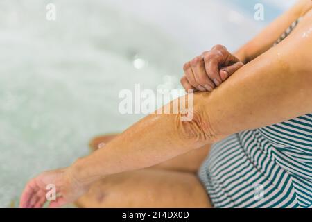 Nahaufnahme der Hände einer älteren Frau in Badeanzug am Pool. Hochwertige Fotos Stockfoto